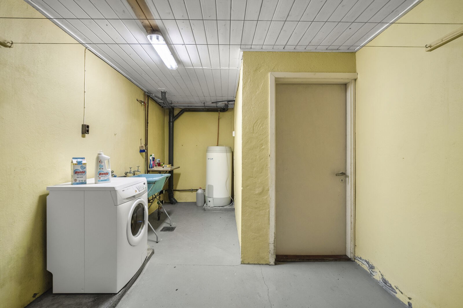 Vaskerom med malt muroverflate paa gulv malte flater paa vegger og panelbord i himling Gulvstaaende utslagsvask og opplegg for vaskemaskin